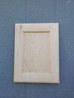 a wooden frame hanging on the side of a building with blue paint and wood grain