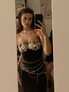 a woman taking a selfie in a mirror with flowers on her chest and chains around her waist