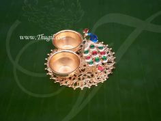 two metal bowls sitting on top of a green surface with a peacock motif around it