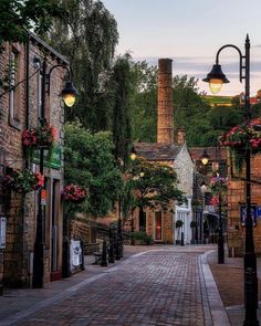 a cobblestone street lined with brick buildings and flowers on either side of the road