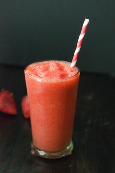 a glass with a straw in it sitting on a table next to some strawberries