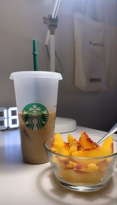 a glass bowl filled with fruit next to a cup of coffee on top of a table