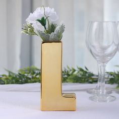 a gold letter shaped vase with flowers in it