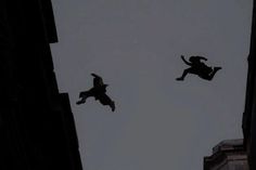 two people are flying through the air on their skateboards in an alleyway at night