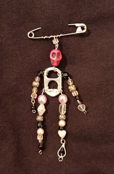 a pink and white beaded robot charm on a brown shirt with silver chain attached to it