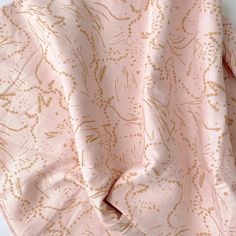 the pink and gold fabric is folded up on top of a white surface with small brown dots