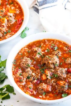 two white bowls filled with meatball soup and garnished with cilantro