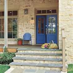 a blue front door on a stone house with steps leading up to it and flowers