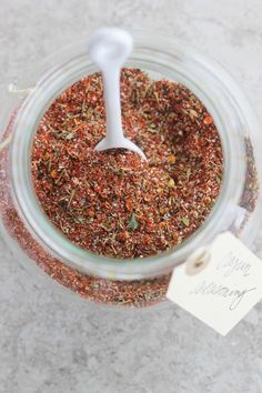 a jar filled with spices sitting on top of a white table next to a tag