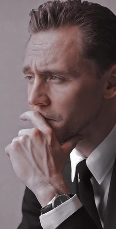 a man in a tuxedo is posing for a photo with his hand on his chin