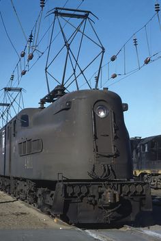 an old train is sitting on the tracks under some power lines and electric wires above it