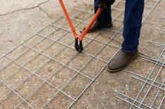 a person is standing on a grate with an orange umbrella attached to the ground