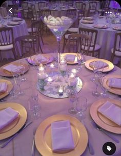 the table is set with plates, silverware and purple linens for an elegant dinner