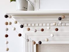 a mantle with a potted plant on top of it next to a string of wool balls