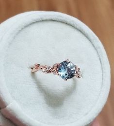 someone is holding an engagement ring with a blue topazte stone in it's hand