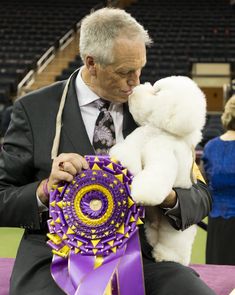 a man in a suit and tie holding a teddy bear