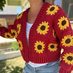 a woman wearing a red crocheted cardigan with sunflowers on it