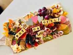 a bunch of food that is on top of a wooden board with the word boy or girl spelled out