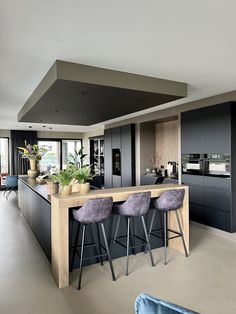 a kitchen with an island and bar stools next to it, in front of a large window