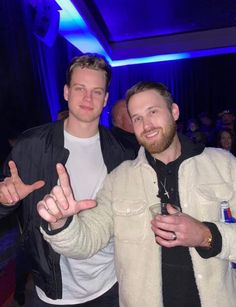 two men standing next to each other at a party