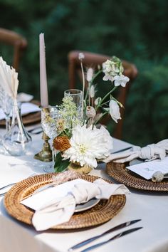 the table is set with white flowers and place settings