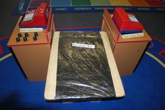 two boxes with plastic covering them sitting on top of a blue rug in front of a game table