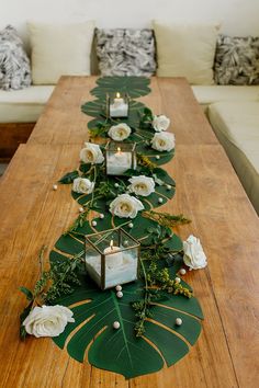 a long table with candles and flowers on it in front of some couches,