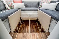 the inside of a camper with wood flooring and storage compartments on each side