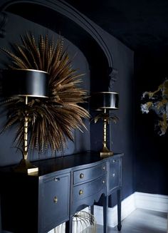 a table with two lamps on top of it next to a black dresser and mirror