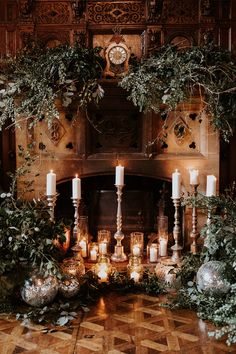 a fireplace with candles and greenery around it