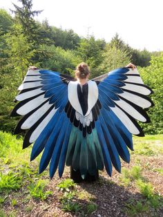 a woman standing in the grass with her wings spread open