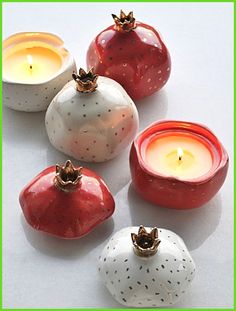 four ceramic apples and two candles sitting next to each other