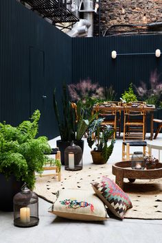 an outdoor seating area with potted plants and candles on the table, surrounded by other patio furniture