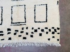 a white rug with black squares and rectangles on the bottom is laying on a floor