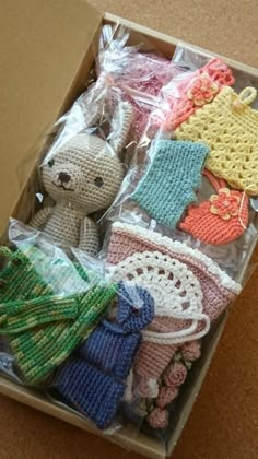 there are many crocheted items in the box on the table, including a teddy bear