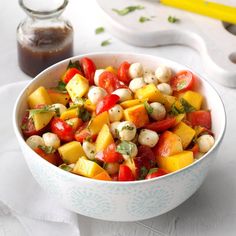 a white bowl filled with lots of food on top of a table next to a spoon