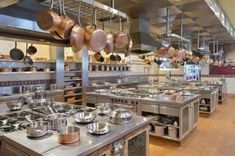 a large kitchen with many pots and pans hanging from the ceiling, along with other cooking utensils