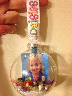 a hand holding a glass ornament with a child's photo on it