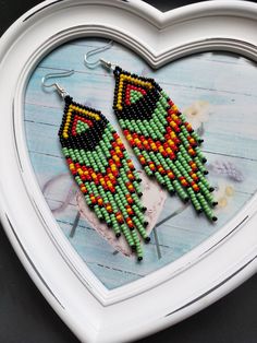 a pair of beaded earrings in the shape of a heart on a white tray