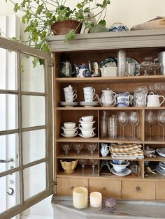 an old china cabinet filled with dishes and cups