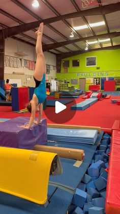 a person doing a handstand on top of blocks in an indoor trampoline course