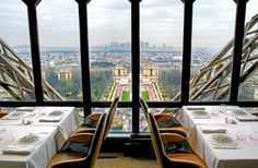 a restaurant overlooking the eiffel tower with tables set up for two people to eat