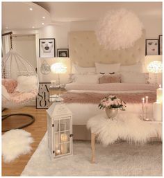 a bedroom decorated in white and pink with feathers on the bed, chandelier