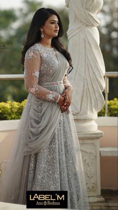 a woman in a long dress standing next to some white statues and looking off into the distance