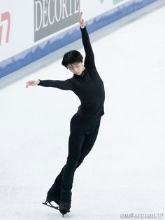 a male figure skating on an ice rink with his arms in the air and one hand up