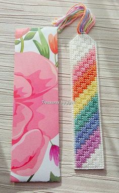 a bookmark with a flower design on it sitting next to a colorful ribbon that reads, rainbow