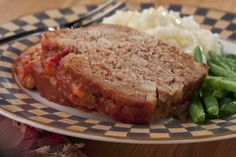 a plate with meatloaf, green beans and mashed potatoes