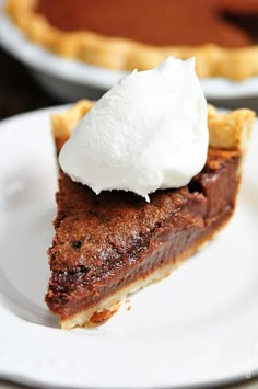 a piece of pie with whipped cream on top sits on a white plate next to another pie