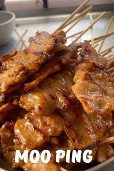 there are skewered meats in a bowl on the table with chopsticks