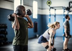 two men and a woman working out with dumbbells in a crossfit gym